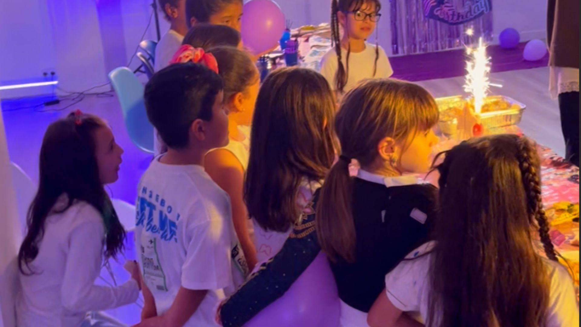 Grupo de niñas y niños alrededor de la tarta con bengala